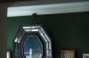 a fireplace in a room with tufted leather sofa and art deco mirror over the mantel filled with objects