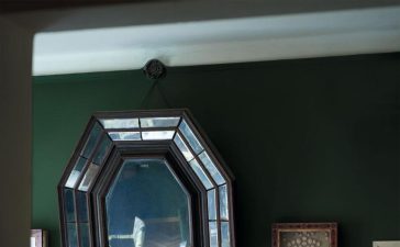 a fireplace in a room with tufted leather sofa and art deco mirror over the mantel filled with objects